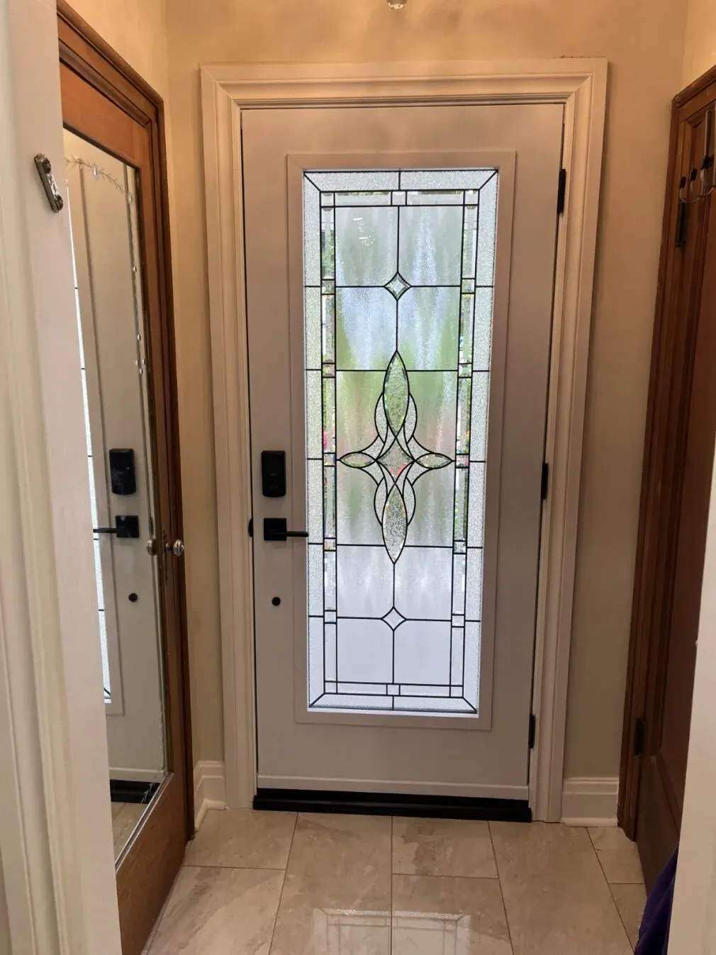 White entry door with decorative leaded glass and smart lock inside a Barrie home